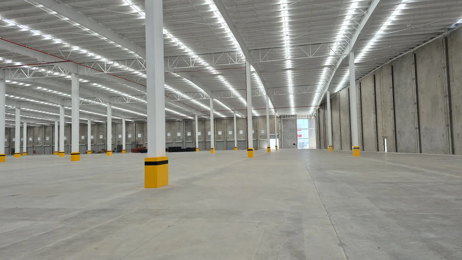 Interior de nave industrial amplia con iluminación LED y muros de concreto